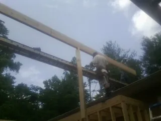 Carpenter setting a ridge beam over a new addition frame — Ice Dam Removal by Roofing Brothers in Marthasville
