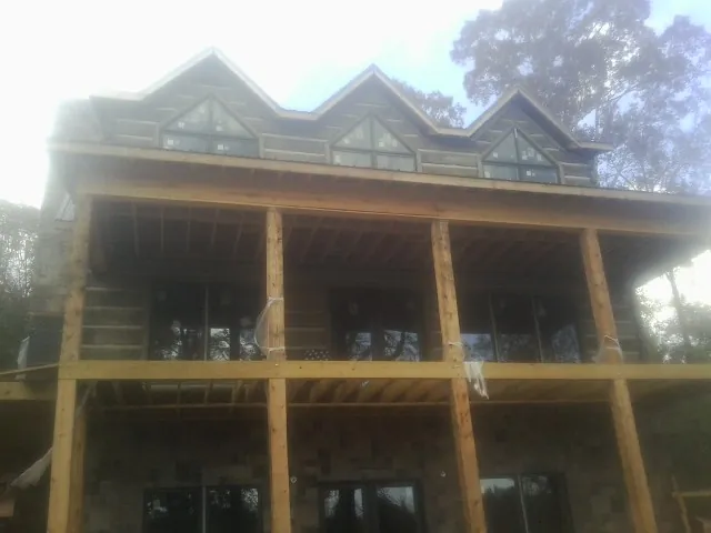 Dormers and porch framing on a large log home under construction — Roof Coating work by our crew in Marthasville