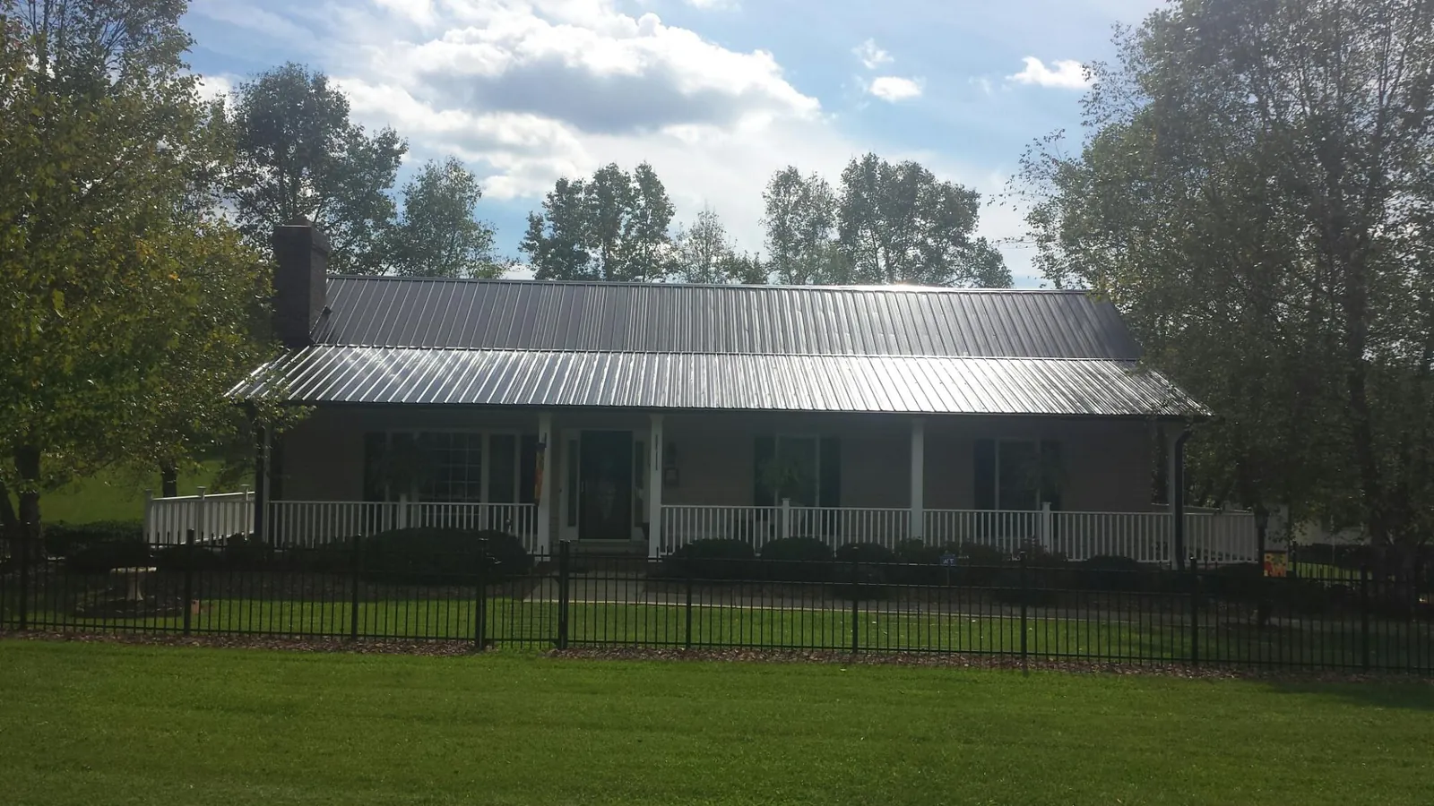 Gray metal roof on a brick ranch with a full width front porch — Gutter Guard Installation work by our crew in Marthasville